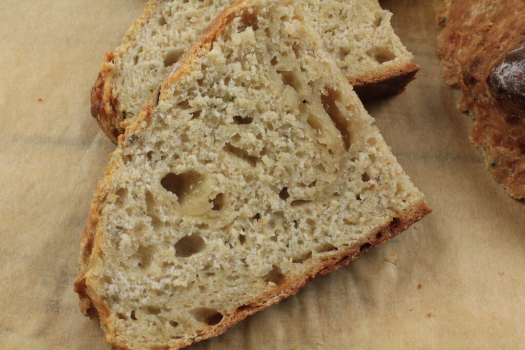 Slice of Sourdough Cheddar Herb Bread showing cheese and moist crumb